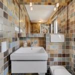 Badezimmer mit farbigen Fliesen, Waschbecken und Toilette.