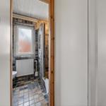 Badezimmer mit gefliestem Boden, Fenster und Dusche.
