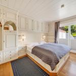 Schlafzimmer mit Bett, Schrank und Blick auf Balkon.