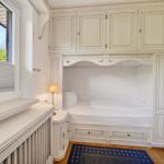 Schlafzimmer mit eingebautem Bett, Schränken und Fenster mit Blick auf Grün.