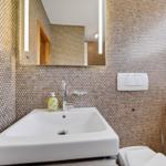 Badezimmer mit Waschbecken, Spiegel und Mosaikwand