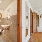 Badezimmer mit Mosaikwand und Toilette. Flur mit Schrank und Holztür.