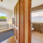 Schlafzimmer mit Schreibtisch und Fenster. Nebenraum mit Toilette und Dusche.