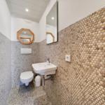 Badezimmer mit Steinwand, Waschbecken, Toilette und Spiegel