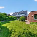 Haus mit Garten, Terrasse und rotem Backsteinbau. Grünflächen und Bäume umgeben die Immobilie.