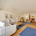 Wohn- und Essbereich mit Sofa, Tisch und Teppichen auf Holzboden.