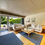 Wohnzimmer mit zwei Sofas, Glas-Tisch und Blick auf Garten.