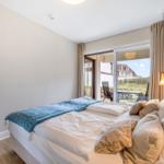 Schlafzimmer mit Bett, Fenster und Blick auf Terrasse