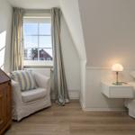Schlafzimmer mit Bett, Nachttisch, Lampe und Fenster mit Blick auf Haus