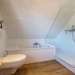 Badezimmer mit Badewanne, Dusche und Toilette unter schrägem Dach