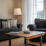 Ein Wohnzimmer mit zwei schwarzen Sofas, einem Holztisch und einem Fenster.