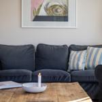 Ein Sofa mit Kissen, eine Kerze und ein Bild an der Wand.