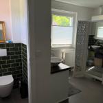Badezimmer mit Toilette, Waschbecken und Duschbereich mit Fenster.