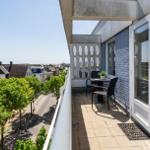 Terrasse mit Tisch und Stühlen, Blick auf grüne Bäume und Straßen