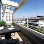 Terrasse mit Tisch, Stühlen und Pflanze. Blick auf Gebäude und Turm.