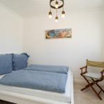 Ein Schlafzimmer mit Bett, Stuhl und Wandbild.
