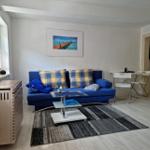 Blauer Sofa mit Kissen, Glas-Tisch und Teppich im Wohnzimmer.