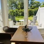 Essbereich mit Tisch und Stühlen, Blick auf Terrasse mit Garten.