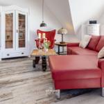 Rotes Sofa, weiße Schrank, Holzboden und Sessel im Wohnzimmer.