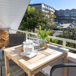 Terrasse mit Tisch, Stühlen und Blumen. Blick auf Wohngebäude und Bäume.