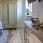 Schlafzimmer mit grünem Schrank, Holzboden und TV über dem Schrank.