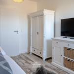 Schlafzimmer mit Bett, Kleiderschrank und TV-Möbel.