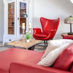 Ein Wohnzimmer mit rotem Sofa, rotem Sessel und weißem Schrank.