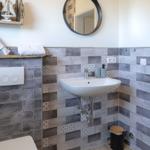 Badezimmer mit Waschbecken, Spiegel und Fliesenwand