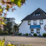 Weißes Haus mit Dachfenster und großem Wanduhr. Blühende Zweige im Vordergrund.