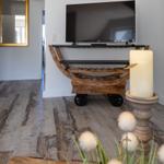 TV auf Holzregal mit Rollen, große Deckenlampe und Kerze auf Tisch
