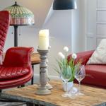 Eckzimmer mit rotem Ledersofa, Holztisch und Pendelleuchte.