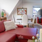 Roter Ledersofa im Wohnbereich mit Essbereich und roter Küchenzeile.