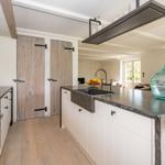 Küche mit Holztür, Steinarbeitsplatte und Glasgefäß.
