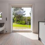 Raum mit Blick auf Garten. Fenster, Sofa, Schrank und Vasen sichtbar.
