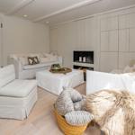 Wohnzimmer mit weißen Sofas, Kamin und Holzboden.