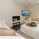 Wohnzimmer mit Sofa, Kamin und Fernseher an der Wand.