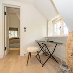 Dachgeschosszimmer mit Schreibtisch, Stuhl und Fenster. Tür führt in Schlafzimmer.
