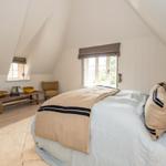 Schlafzimmer mit Dachschrägen, Bett, Fenster und Holzboden.