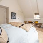 Schlafzimmer mit Dachschrägen, Bett, Stuhl und Fenster