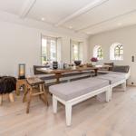 Esszimmer mit Holztisch, Sitzbänken und Fenstern zum Garten.