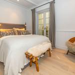 Schlafzimmer mit Bett, Holzbank, Stuhl und Fenster