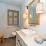 Badezimmer mit Waschtisch, Spiegel, Toilette und Dusche