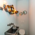 Badezimmer mit Waschbecken, Toilette und Wandbeleuchtung.