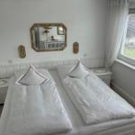 Schlafzimmer mit Doppelbett, zwei Nachttischen und Spiegel an der Wand.