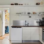 Kitchen with white cabinets, stainless steel sink, and open shelves with dishes.