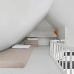 Room with two mattresses and white staircase in attic.