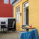 Terrace with table, chairs, and blue towel against yellow house wall.