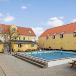 Pool area with yellow buildings and patio furniture.