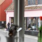 View from inside shows a street scene with a pink shop and a red house.