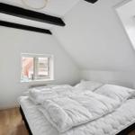 Bedroom with skylight, bed and wooden floor. A mirror hangs on the wall.